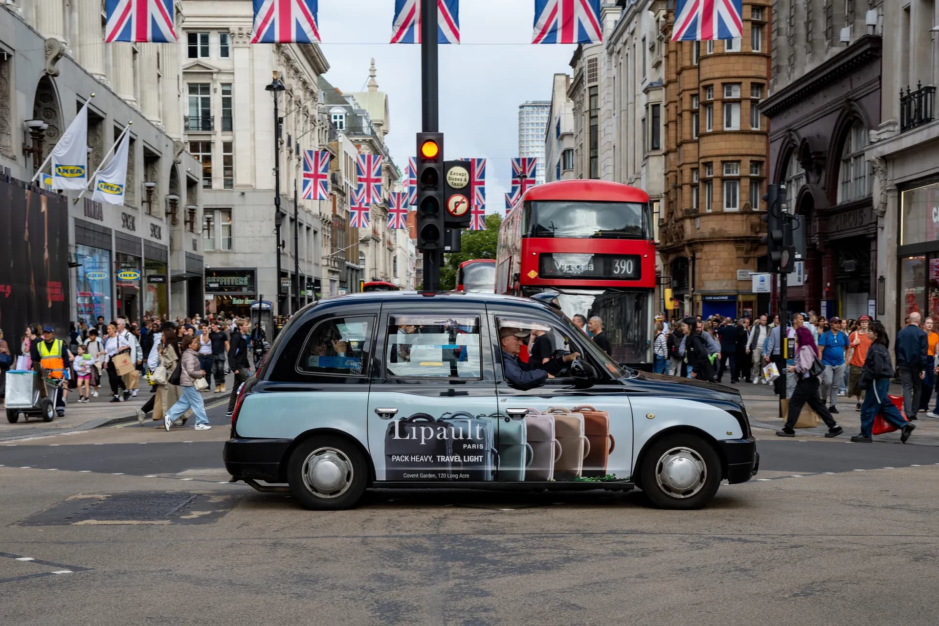 Lipault-branded taxi at Oxford Circus under Union flags, a red bus behind